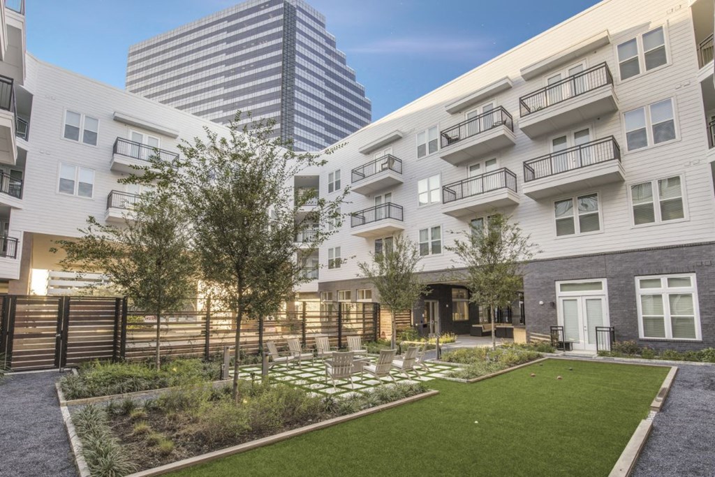 a courtyard with grass and trees in front of buildings