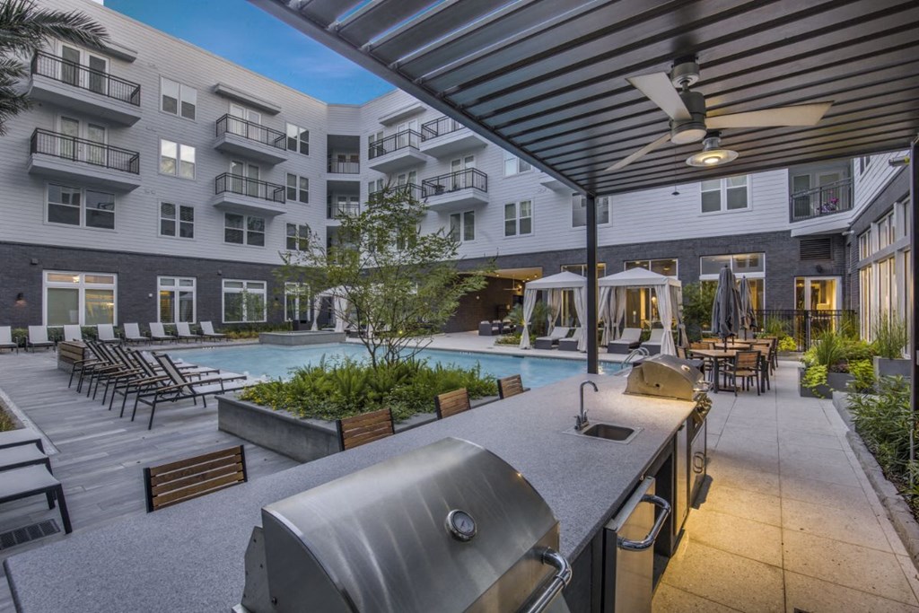a patio with a grill and a pool in front of an apartment building