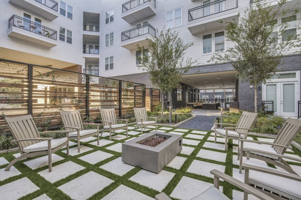 a courtyard with chairs and tables and a fire pit