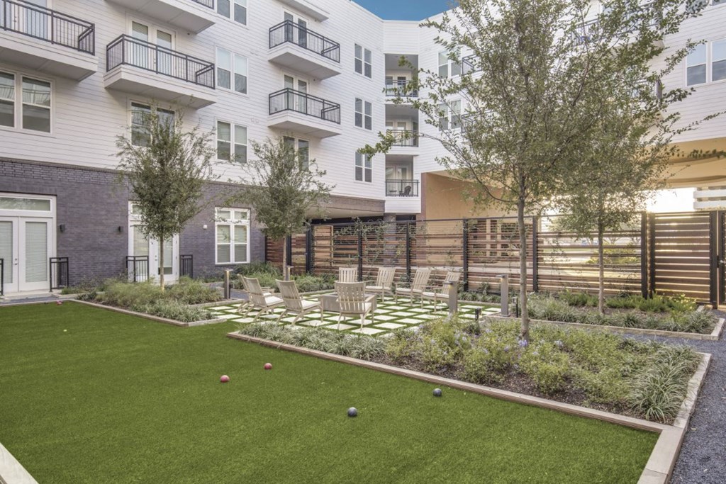 a courtyard with a lawn and bocce balls in front of an apartment building