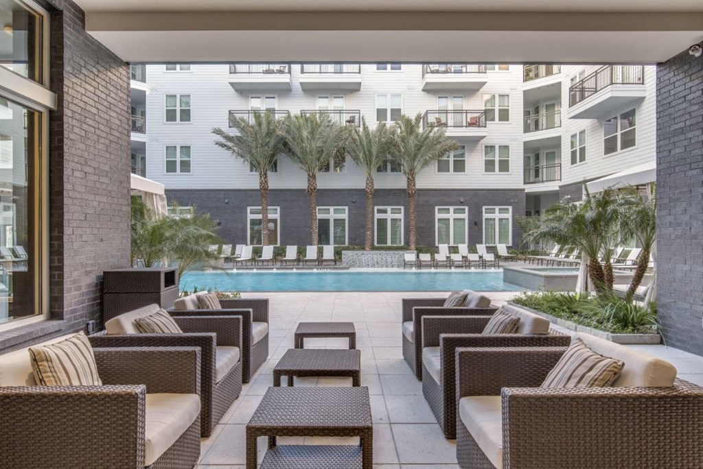 a pool with chairs and tables in front of an apartment building