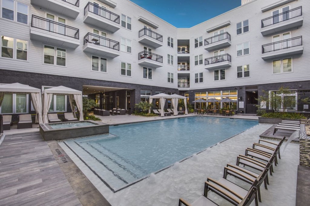 an outdoor pool with chairs and an apartment building