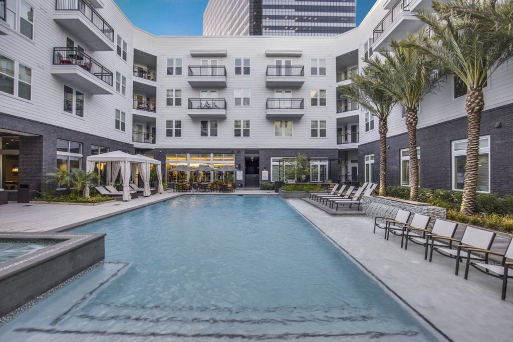 a swimming pool in front of a white building with palm trees
