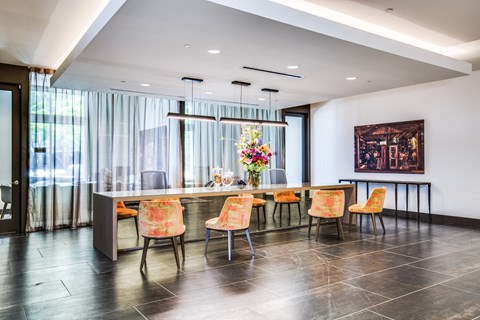 A dining room with a table set for six with orange chairs.
