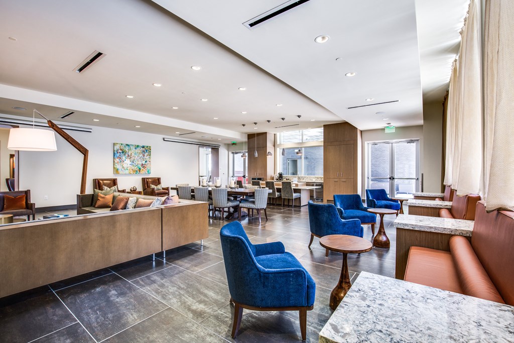 a lounge area with blue chairs and tables and a reception desk