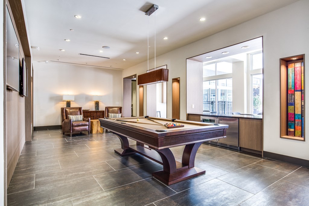 a game room with a pool table in the middle of it