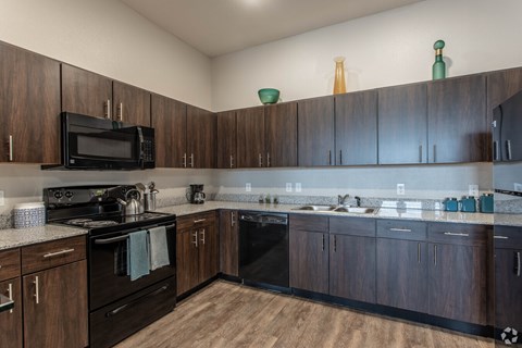 A kitchen with dark wood cabinets and black appliances.