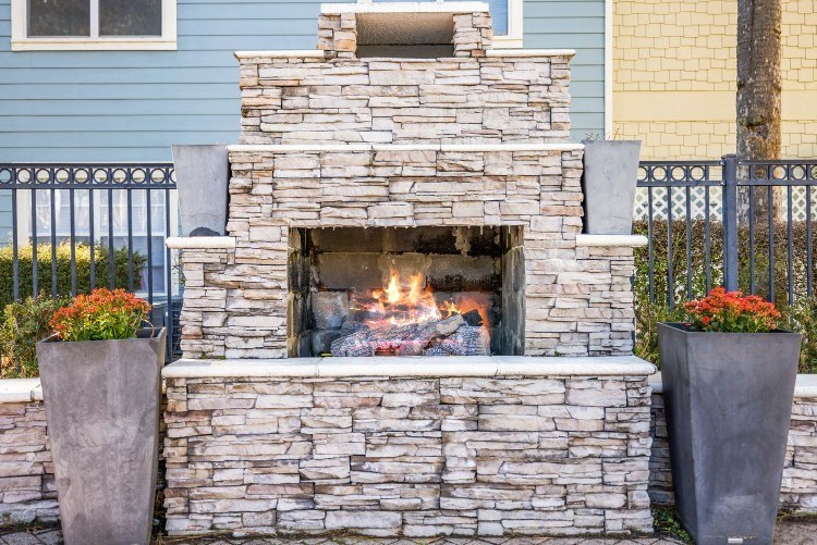 a stone outdoor fireplace in front of a house
