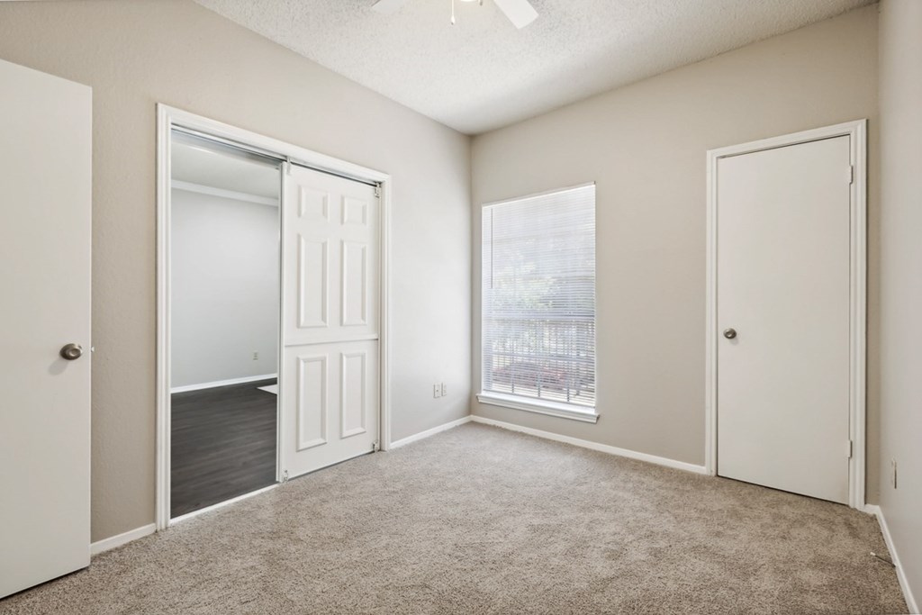 A room with a carpeted floor and a window showing a cityscape.