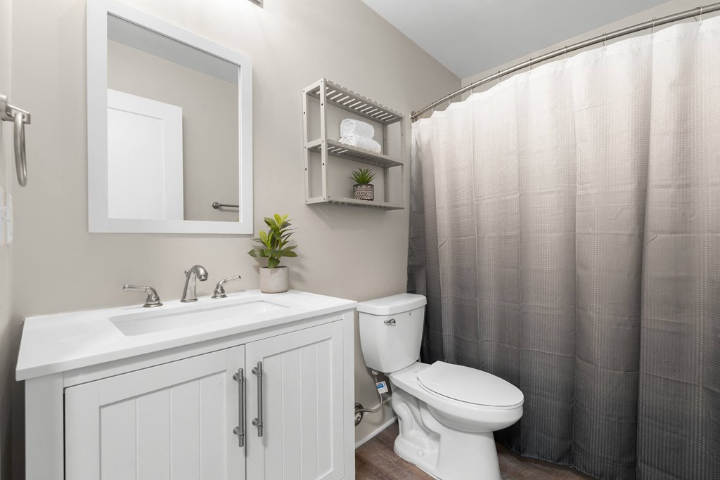 A white bathroom with a toilet, sink, and shower curtain.