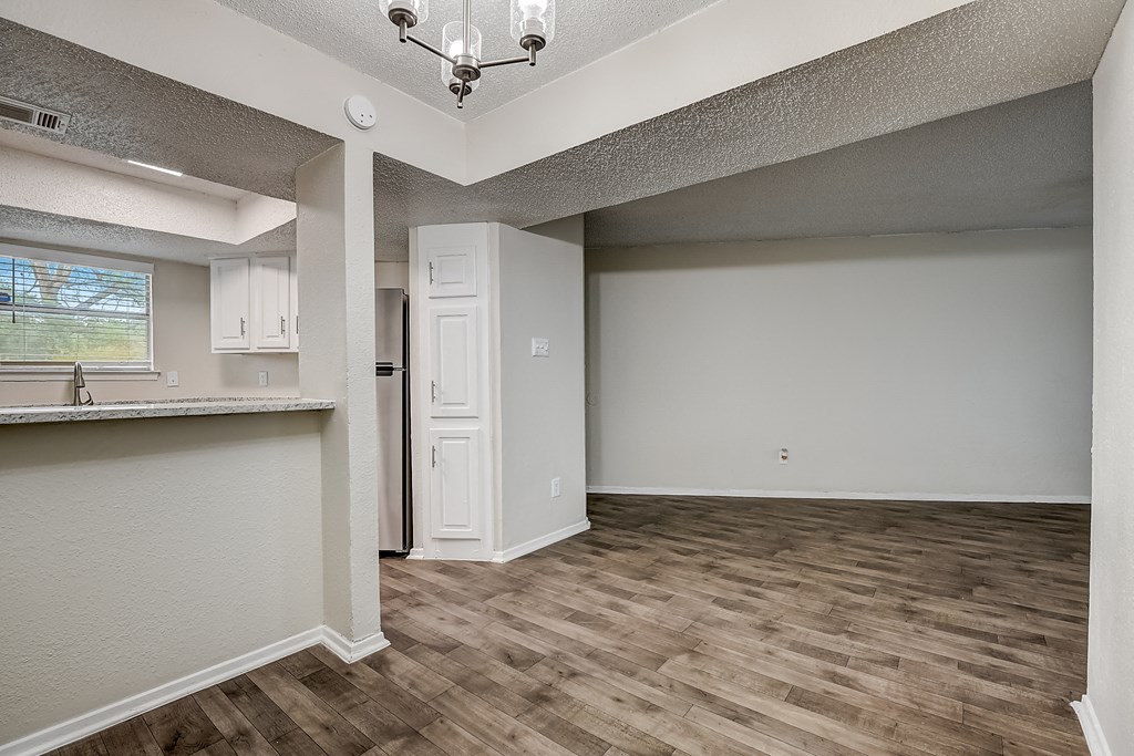 a kitchen and living room with hardwood floors and a chandelier