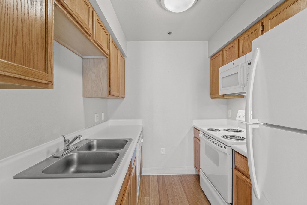 a kitchen with white appliances and wooden cabinets and a sink