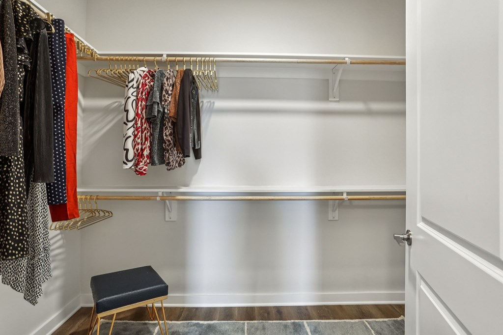 A hallway with a bench and clothes hanging on a rail.