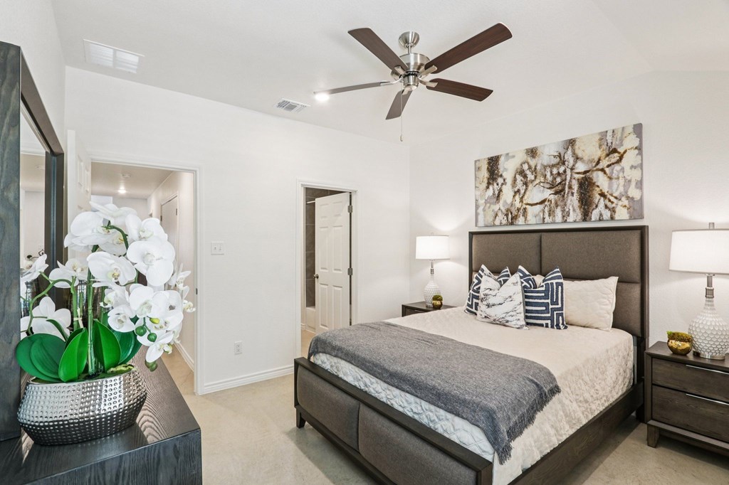 A bedroom with a bed, nightstand, and a ceiling fan.