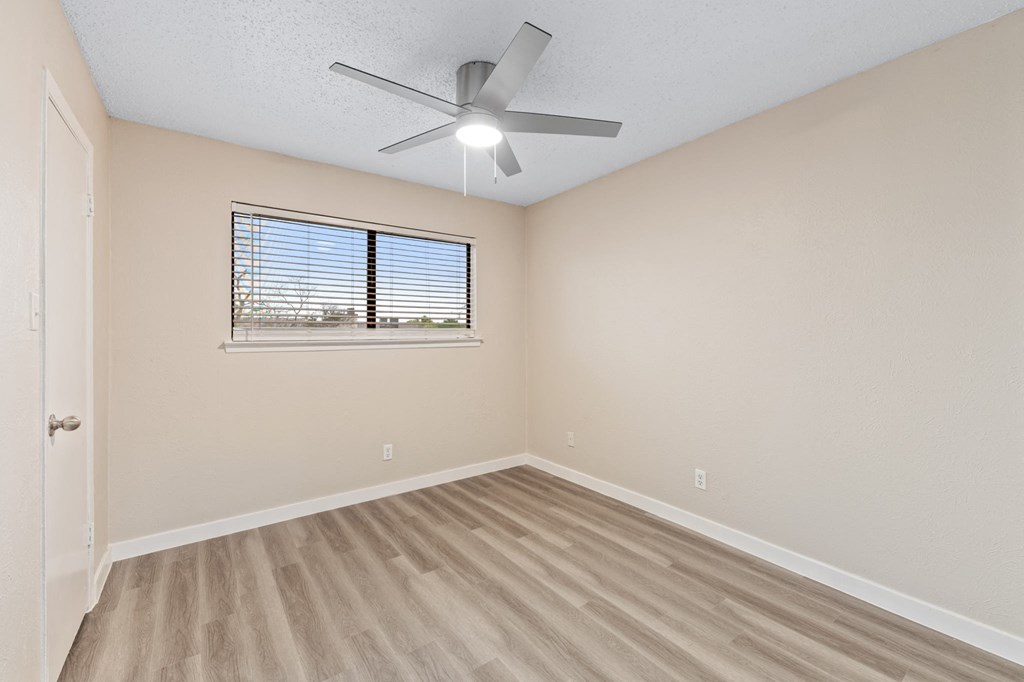 an empty bedroom with a ceiling fan and a window