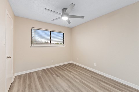 an empty bedroom with a ceiling fan and a window