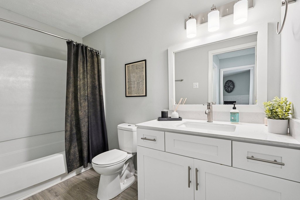 A white bathroom with a toilet, sink, and mirror.