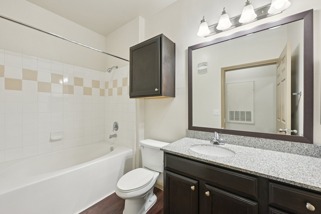 A bathroom with a white toilet, a bathtub, and a sink.