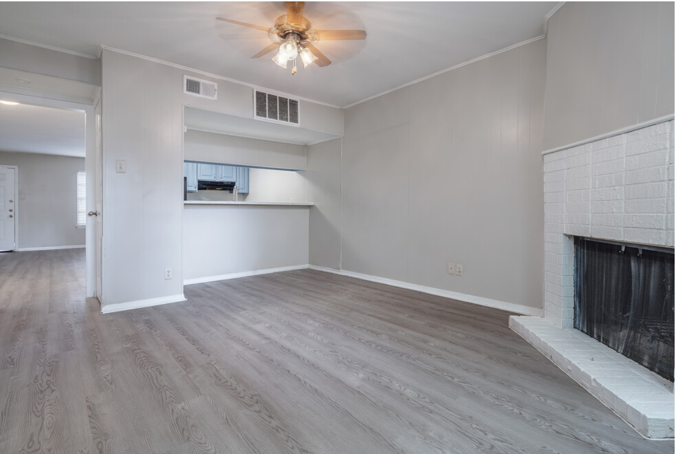 an empty living room with a fireplace and a ceiling fan