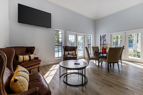 A living room with a brown leather couch and a black television mounted on the wall.