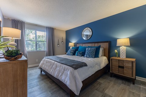 A bedroom with a large bed and a wooden nightstand.