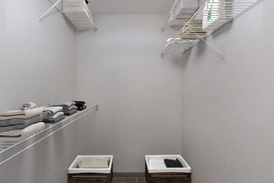 A laundry room with a white wall and a metal rack.