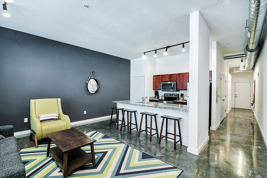 a living room with a bar and a kitchen with stools