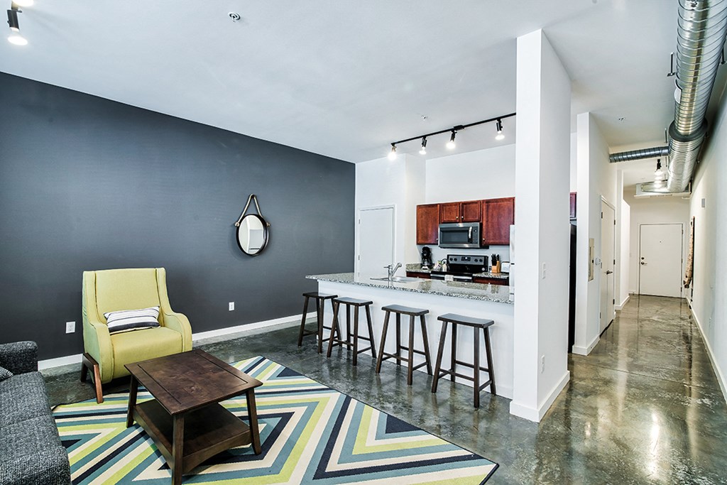 a living room with a bar and a kitchen with stools