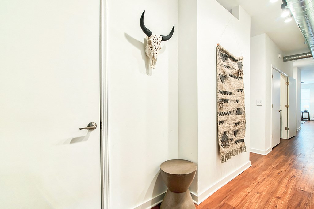 a hallway with a cow skull on the wall and a wooden stool