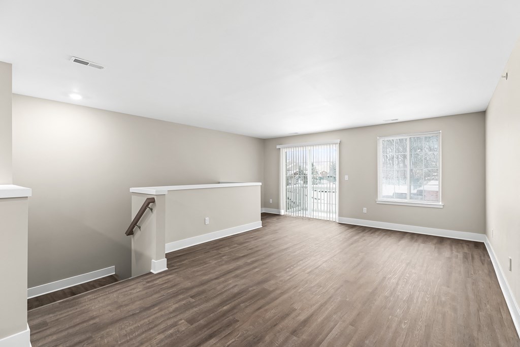 an empty living room with wood flooring and a window