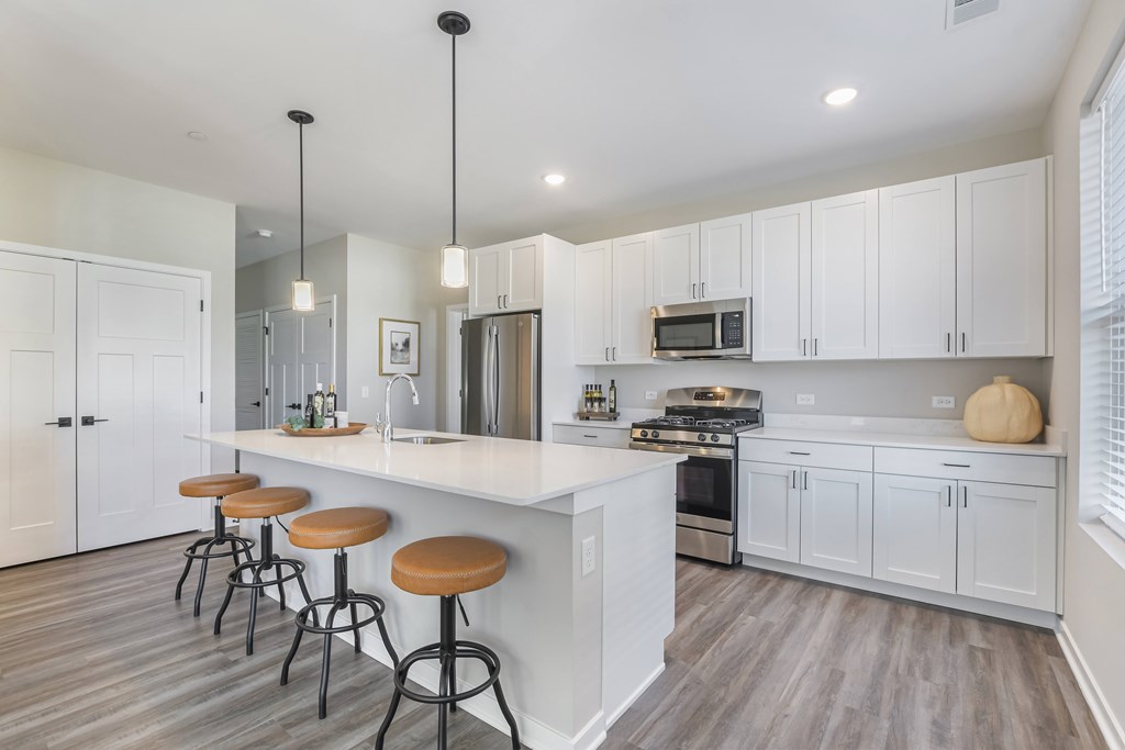 A kitchen with white cabinets and a bar area with stools.