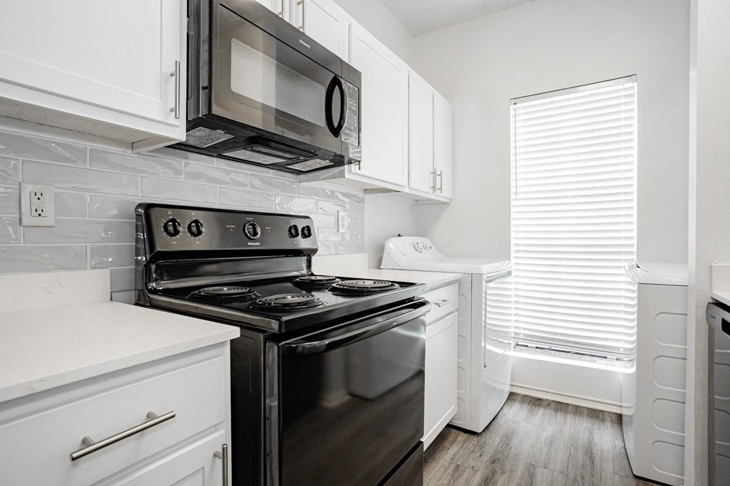 an all white kitchen with black appliances and white cabinets