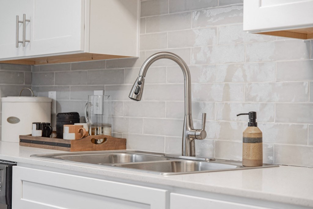 A kitchen sink with a soap dispenser and a coffee maker on the counter.