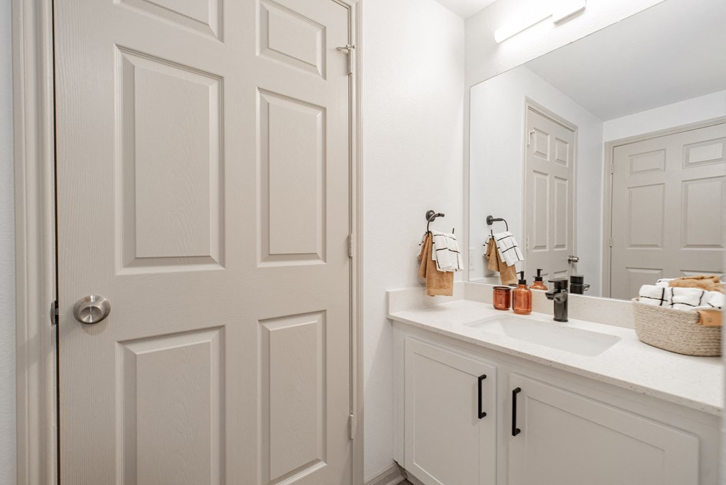 a bathroom with white cabinets and a sink and a mirror