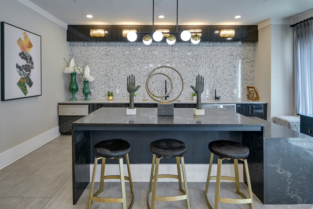 A kitchen with a bar area featuring a marble countertop and gold bar stools.