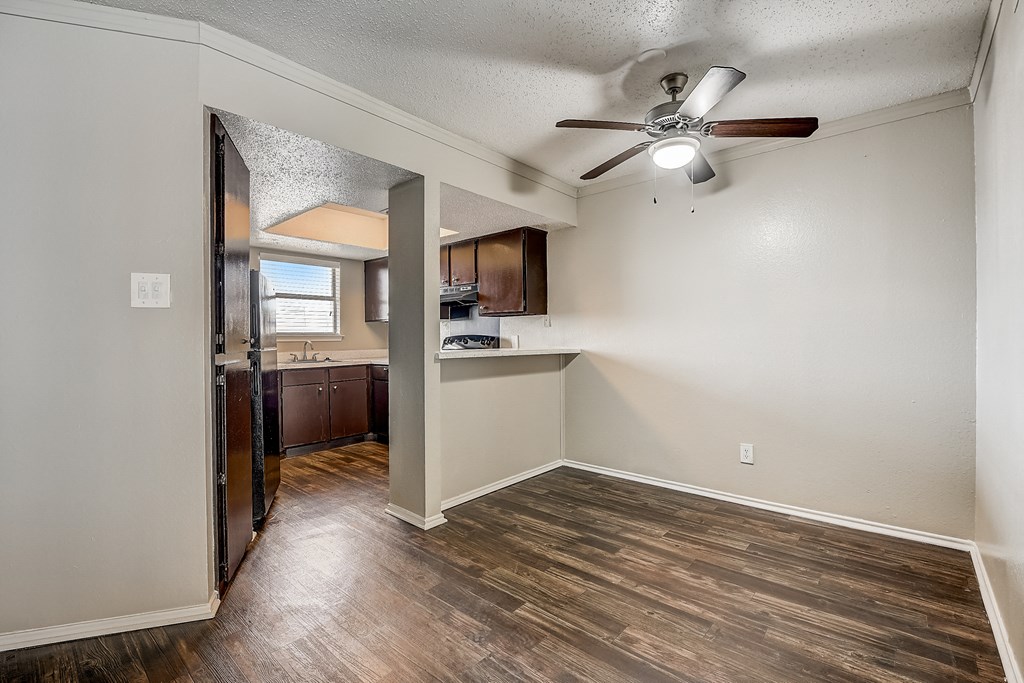 a bedroom with a ceiling fan and a kitchen in the background