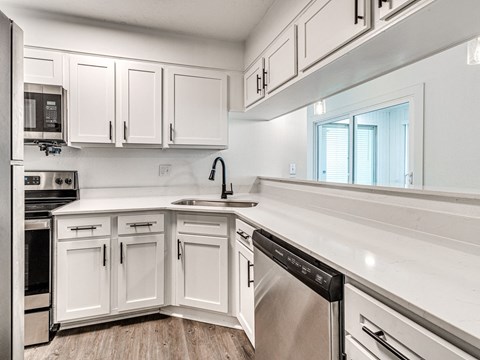 A modern kitchen with white cabinets and stainless steel appliances.