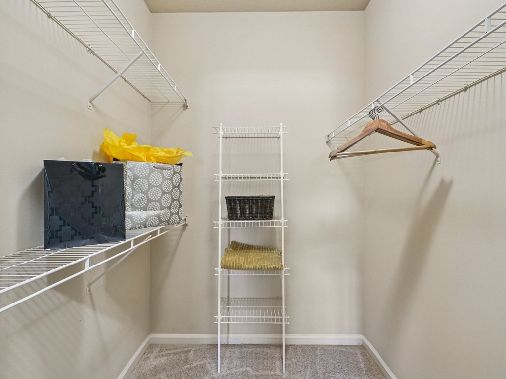 A walk-in closet with a hanger and shelves.