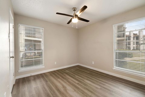 a bedroom with two windows and a ceiling fan