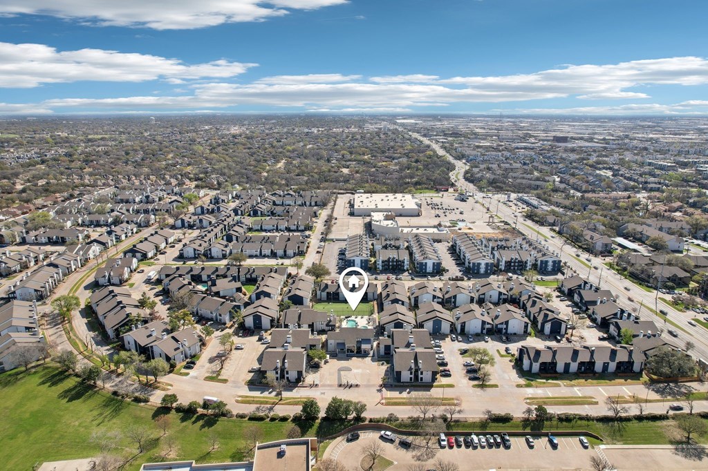 A bird's eye view of a residential area with a large green space in the foreground.