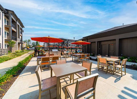 A patio with tables and chairs and umbrellas.