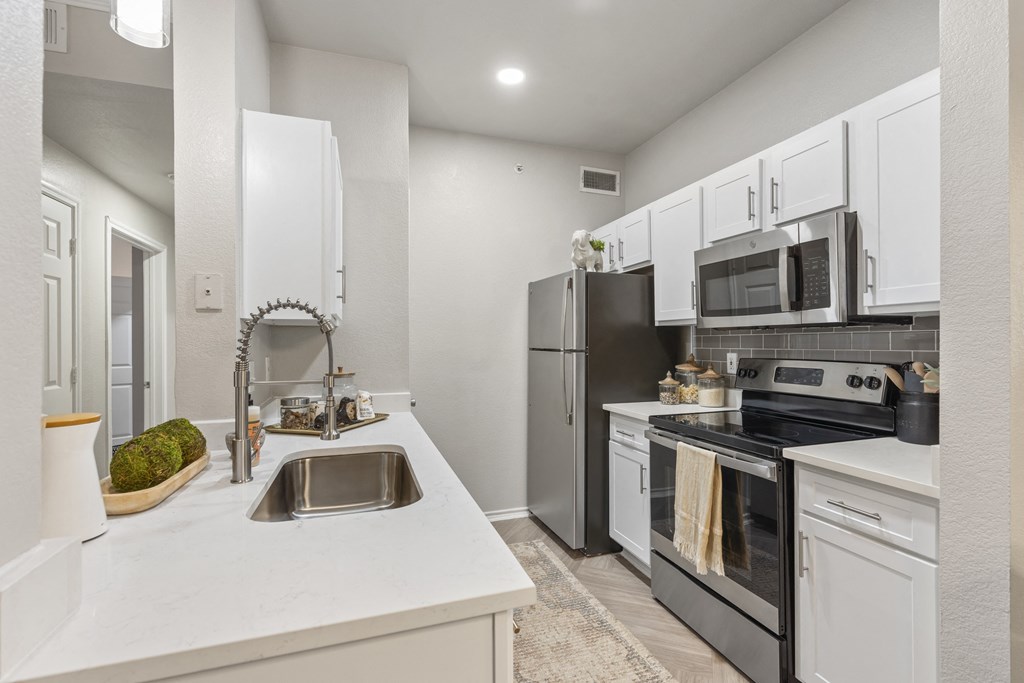 a white kitchen with stainless steel appliances and white counters