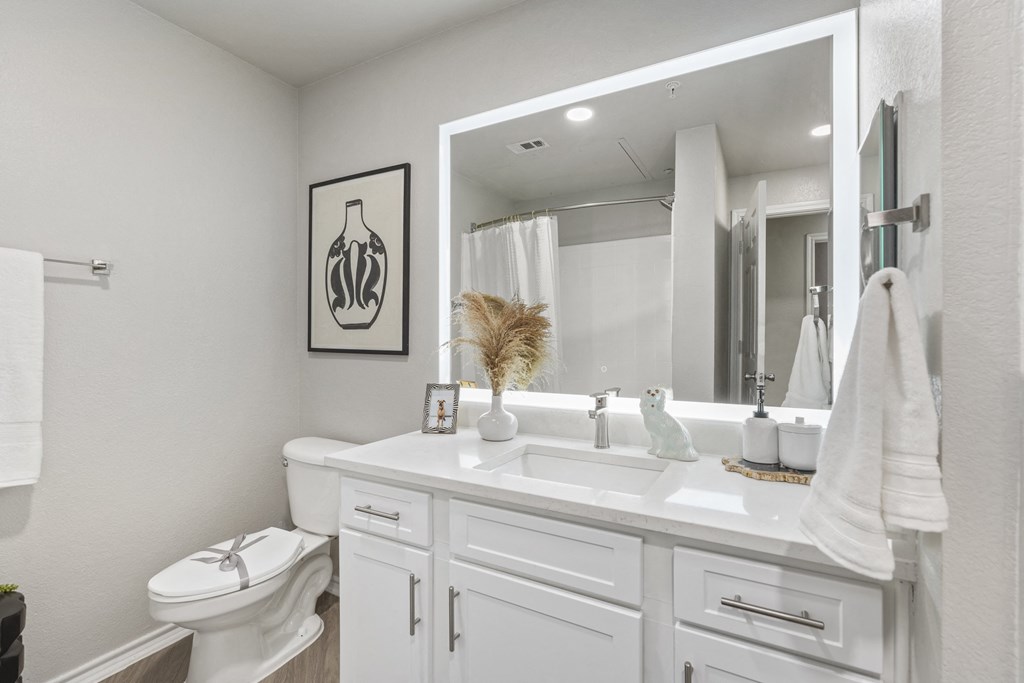 a white bathroom with a large mirror and a white toilet and sink