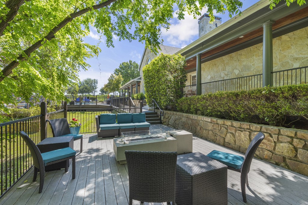 a backyard patio with tables and chairs and a fire pit