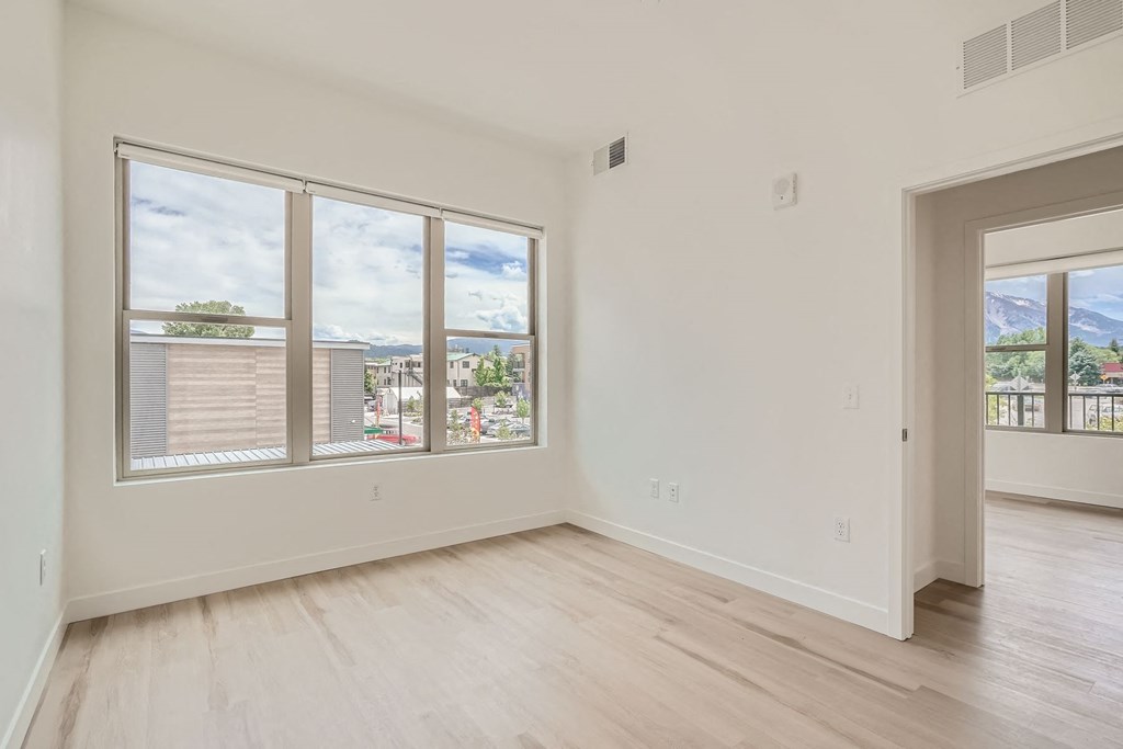 a bedroom with a large window and hardwood floors