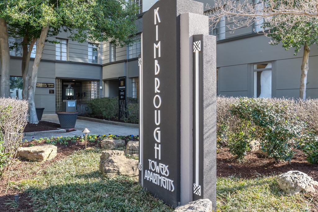 a monument sign in the grass in front of a building