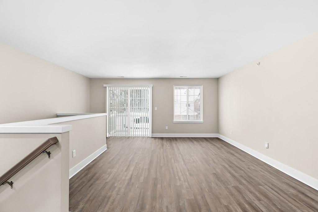an empty living room with wood flooring and a window