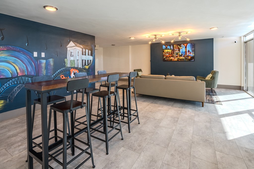 a bar with stools in a living room with a couch and a wall mural