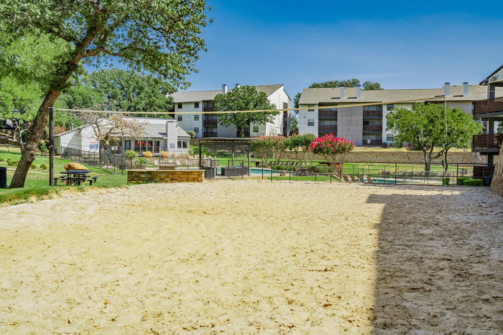 a sandy playground with buildings in the background and trees