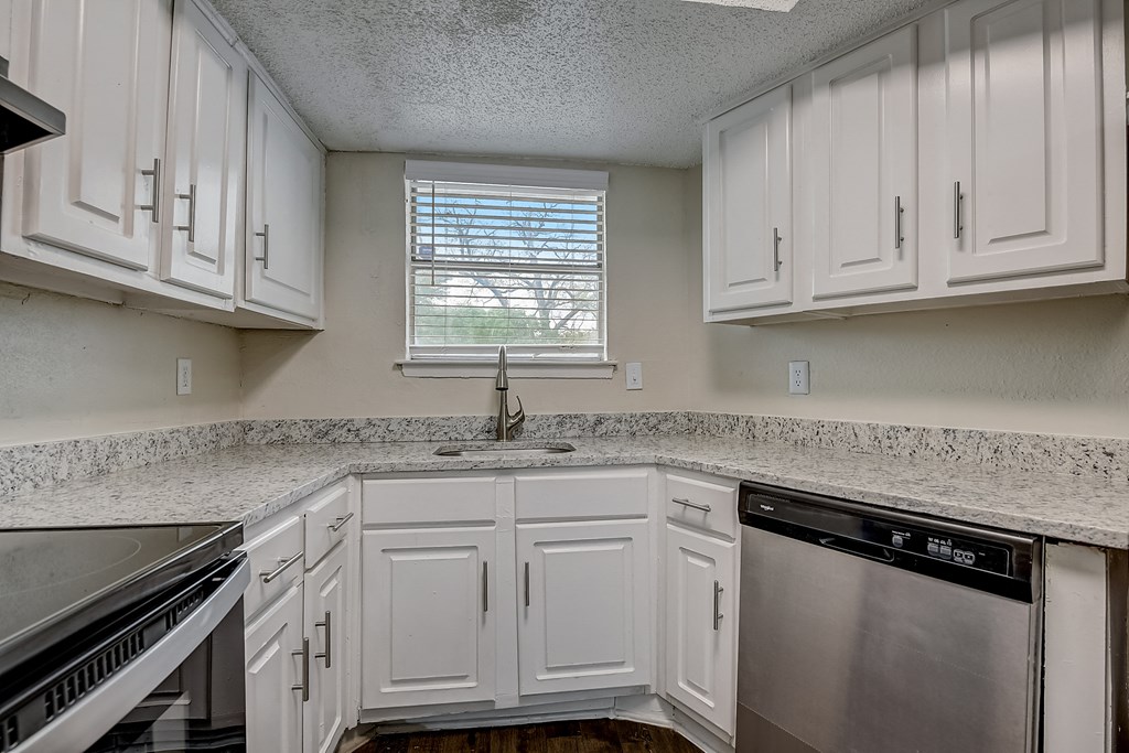 a kitchen with white cabinets and granite counter tops